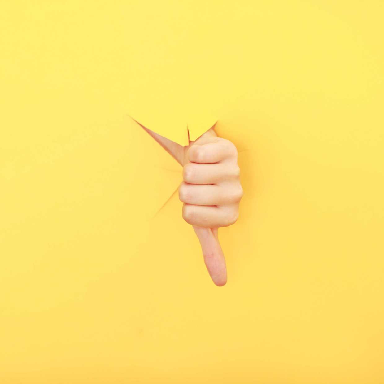 Ein Daumen nach unten vor gelbem Hintergrund als Symbol der Kritik an den Entlassungen der Post